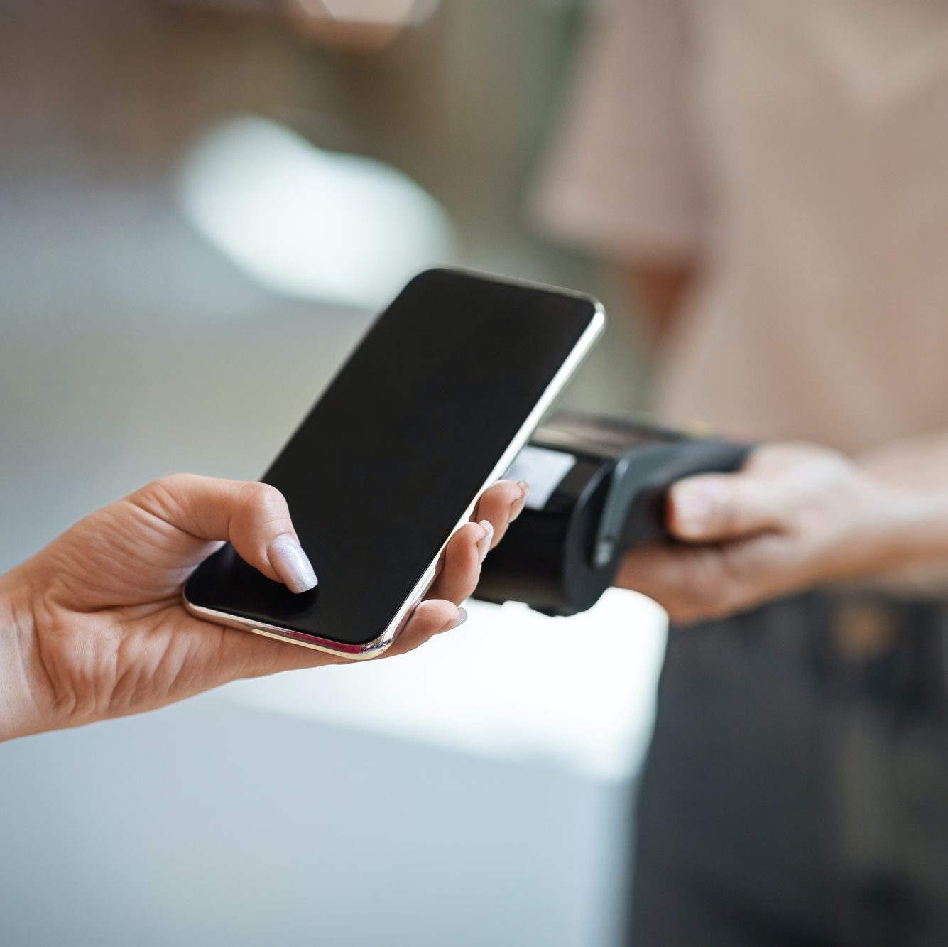 Wireless Payment. Close up female hand using smartphone, paying contactless at cafe